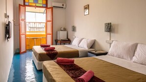 A hotel room with two beds, a small table, a TV, and a window with a view.
