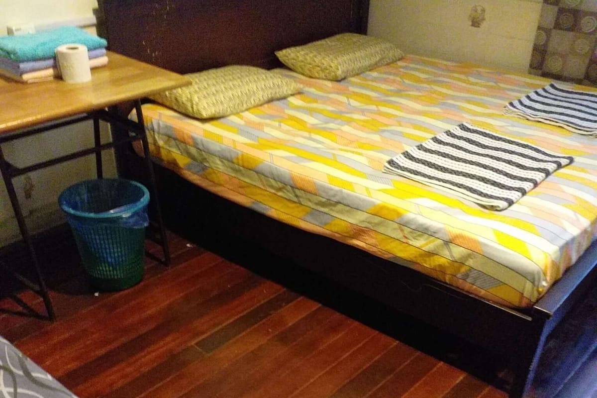Un dormitorio con cama de madera, una mesita con una cesta y un sofá estampado.