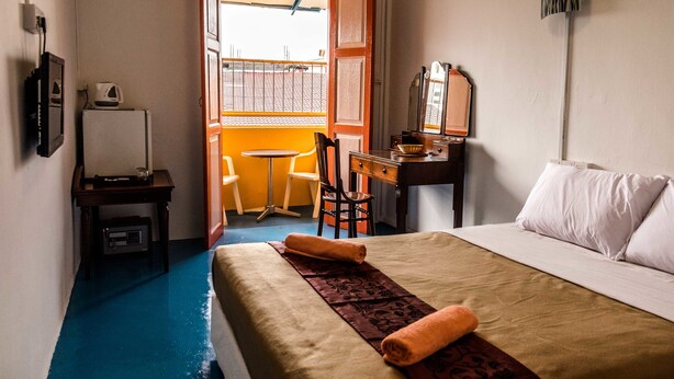 A hotel room with a bed, a desk, a chair, a small table, and a window with a view of the outside.