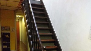 A staircase with wooden steps and black handrails, leading to a landing area with a white wall and a door at the end.