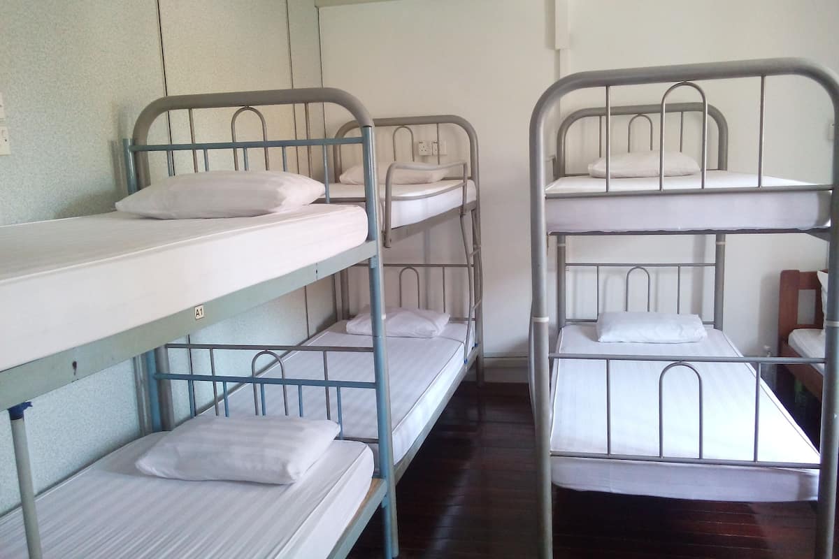Un dormitorio con literas, cada una con almohada y estructura metálica.