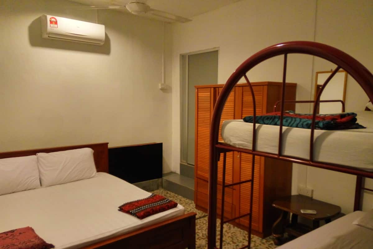 Una habitación con literas, una cama individual, un armario y un aire acondicionado.