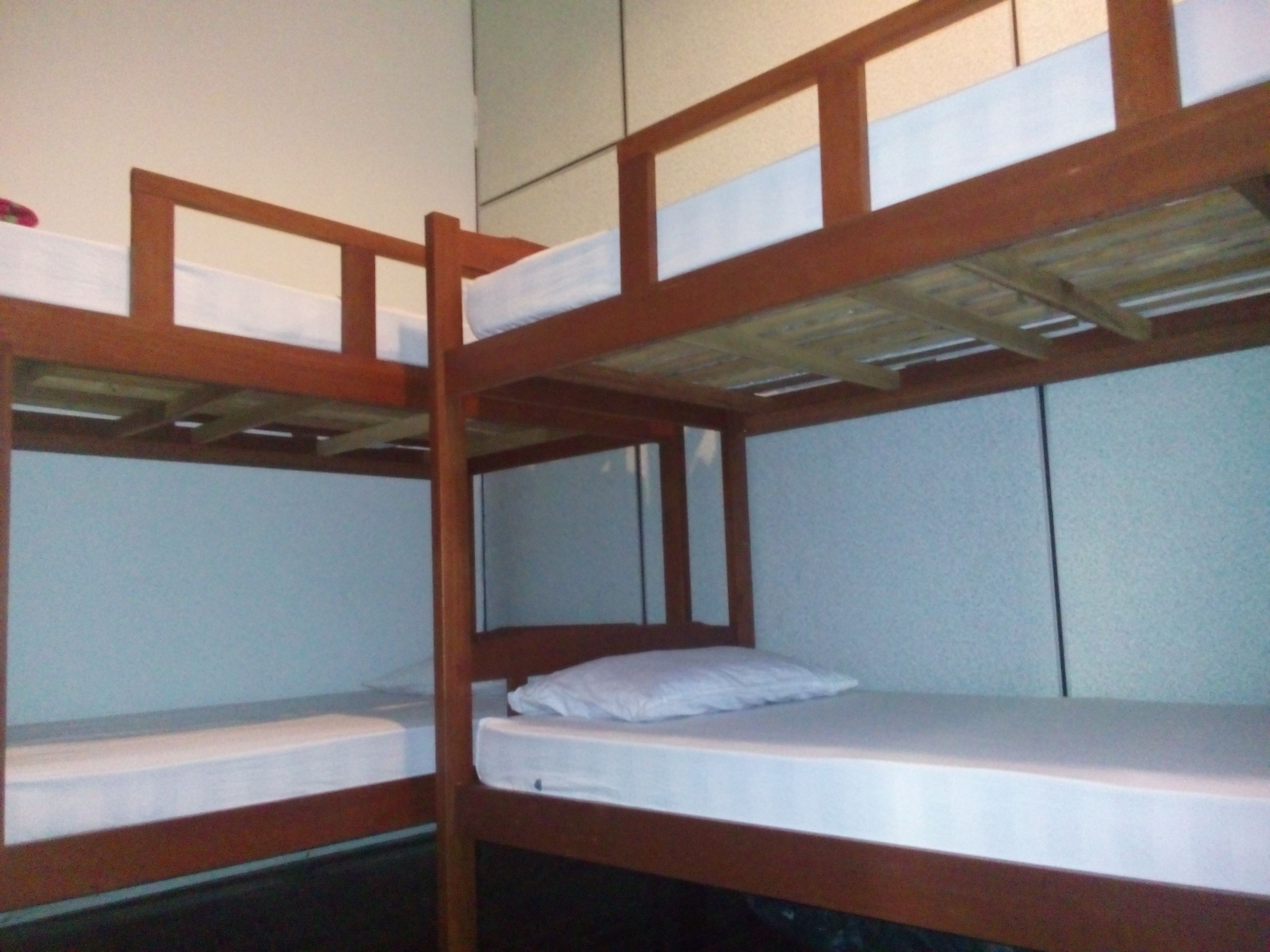 Dormitorio con literas de madera y ropa de cama blanca.