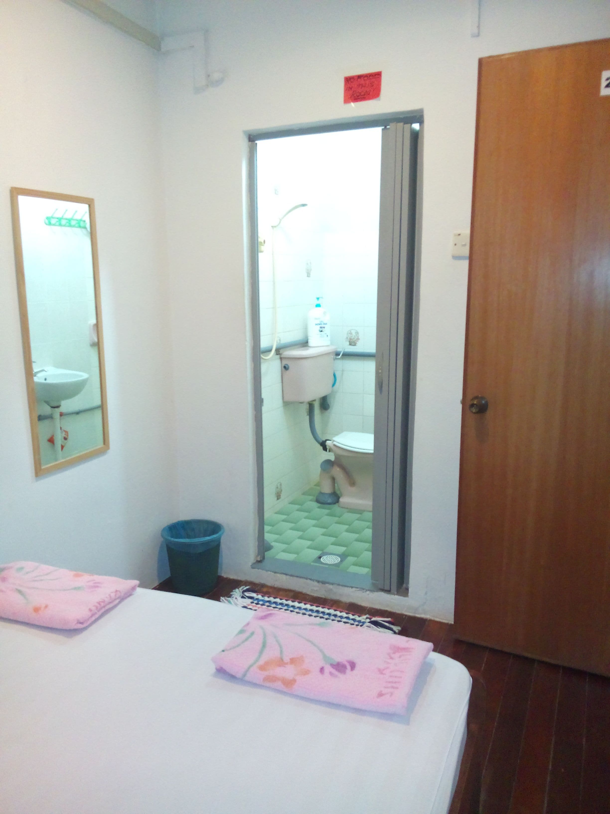 Une chambre à coucher comprenant un lit, un miroir, une porte et une vue sur une salle de bain avec des toilettes et un lavabo.