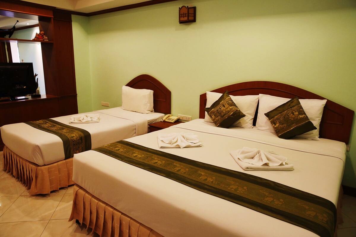 Two twin beds with white linens and decorative pillows, a wooden headboard, and a small bedside table with a telephone.