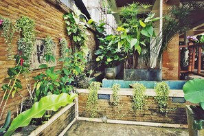 A courtyard with various potted plants, a wooden bench, and a brick wall. - Baan SS Karon (Karon)