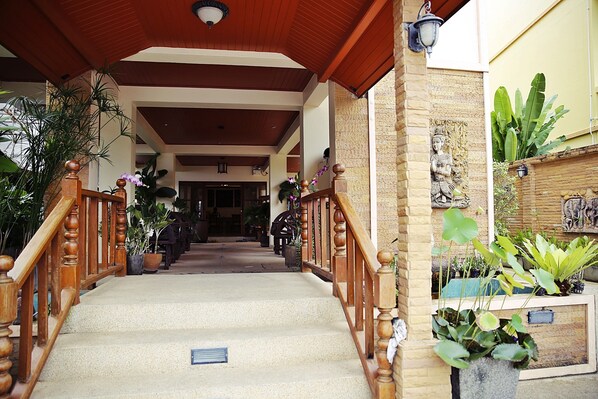 A covered outdoor staircase with wooden railings and potted plants. - Baan SS Karon (Karon)