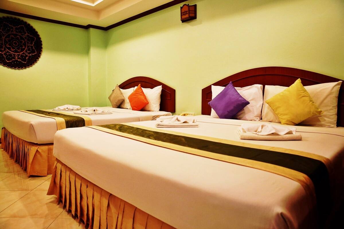 A hotel room with two beds, each with a wooden headboard, white bedding, and multiple pillows.