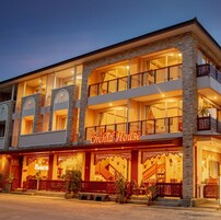 A multi-story hotel with a prominent "Orchid House" sign, featuring balconies, large windows, and a stone facade.