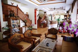 A spacious living area with a wooden staircase, a bookshelf, and a dining area with chairs and a table.