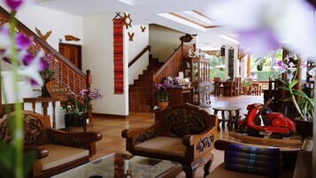 A spacious lobby with wooden furniture, a staircase, and a view of the outdoor area.