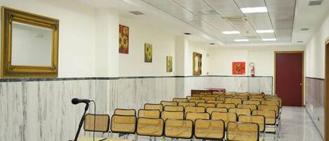 A conference room with rows of chairs, a podium, and a large table.