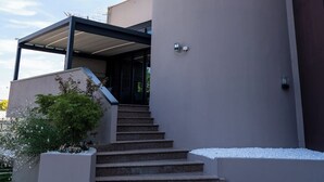 Un edificio moderno con una torre curva, un acceso cubierto y una escalera que conduce a la entrada.