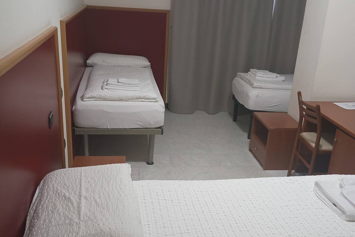 A hotel room with a large bed, a smaller bed, a desk, and a chair.