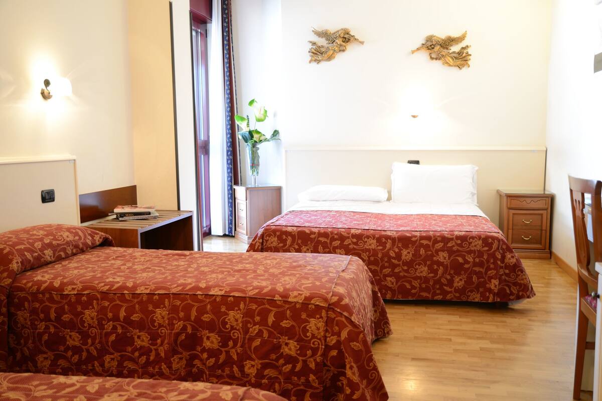 A hotel room with two beds, a bedside table, a nightstand, and a decorative wall piece.