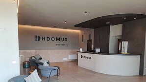Una moderna zona de recepción con mostrador curvo, un sofá y dos sillones.