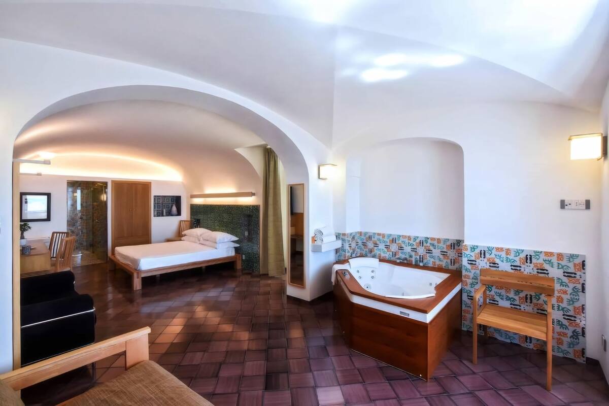 Une pièce spacieuse avec un grand lit, une baignoire en bois et un coin salon.