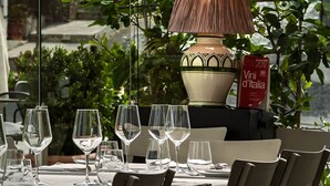Una mesa servida con copas de vino y una lámpara, con un libro titulado 'Vini d'Italia' sobre la mesa.