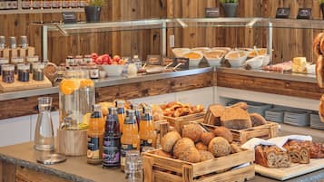Zona de bufé con diversas opciones de comida, incluyendo pan, frutas y salsas.