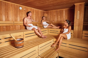 En sauna med træbænke og en træspand med en si.