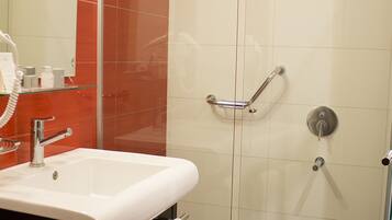 Un baño con ducha de vidrio, lavamanos blanco y espejo.