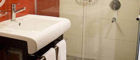 A bathroom with a glass-enclosed shower, a white sink, and a mirror.