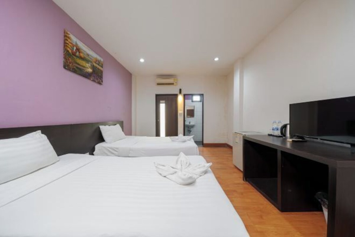 Habitación de hotel con dos camas, televisión y escritorio.