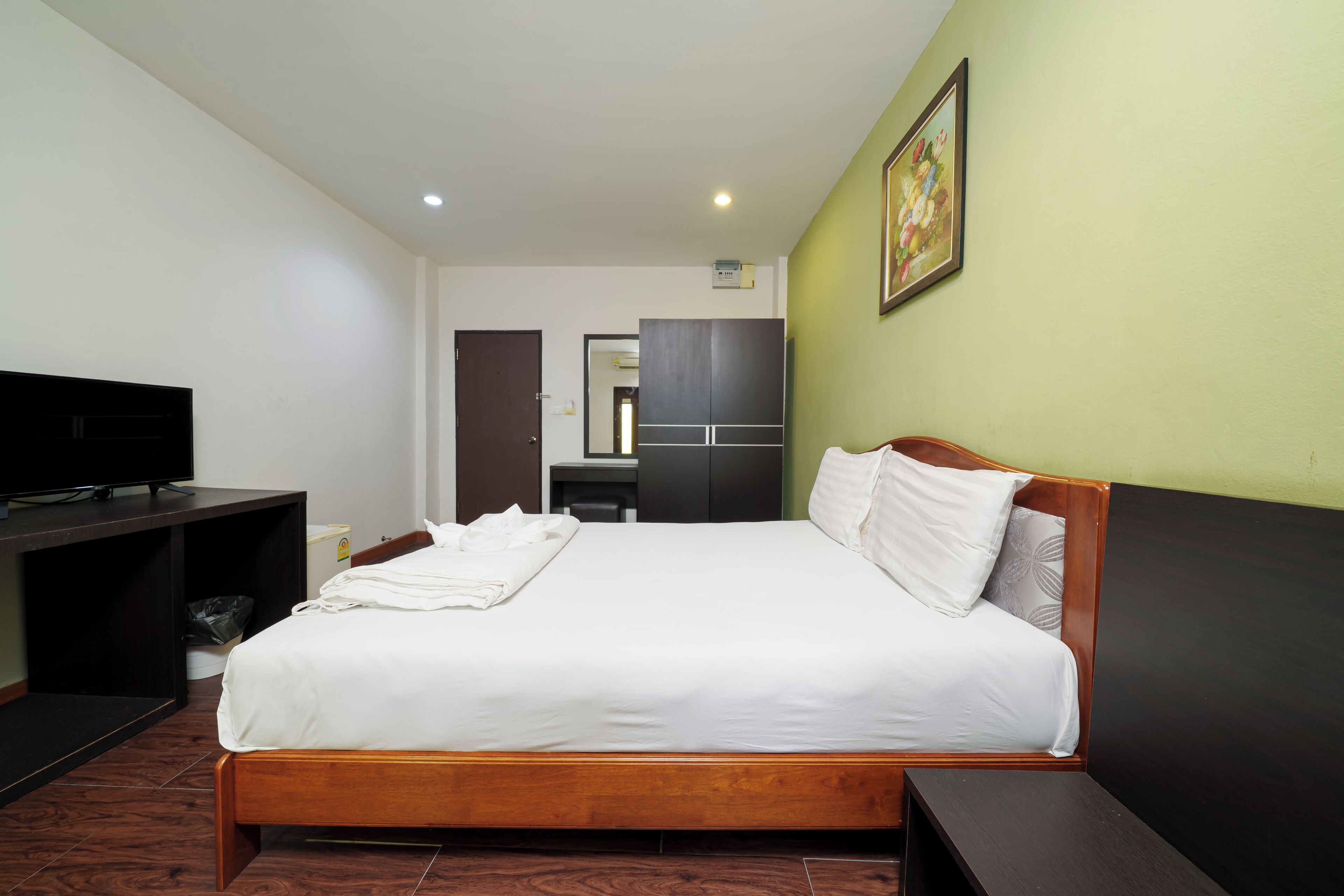 A hotel room with a bed, a television, a desk, and a wardrobe.