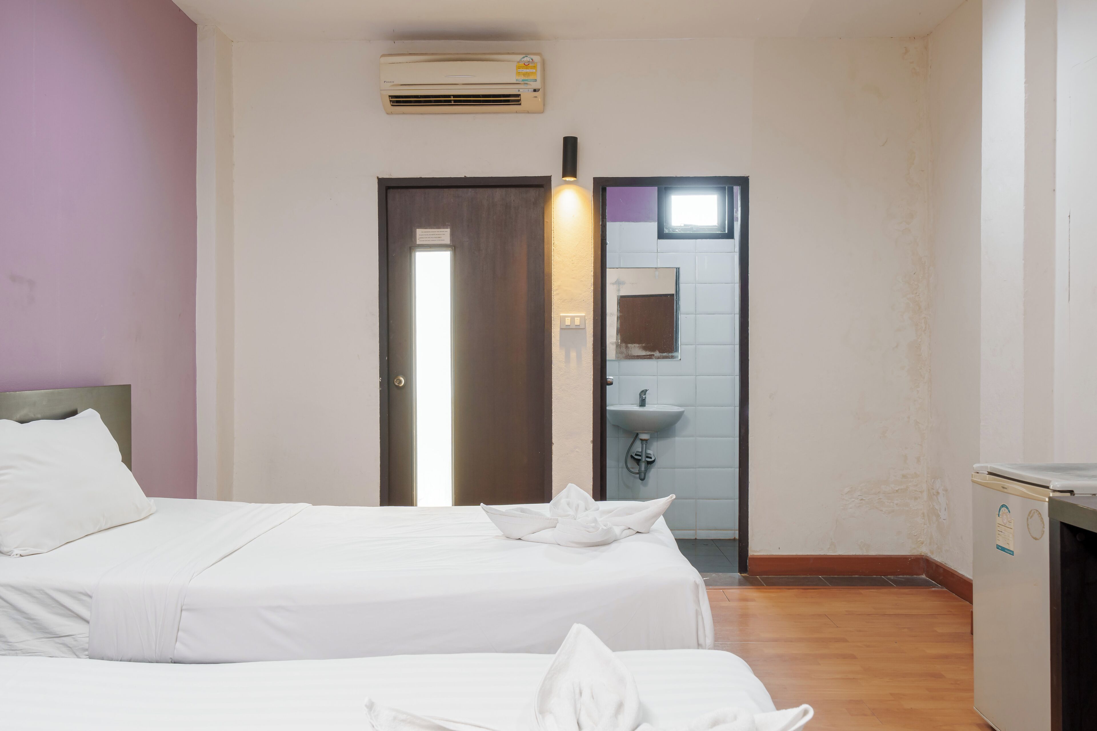 A hotel room with two beds, a bathroom with a sink, and a small kitchenette.