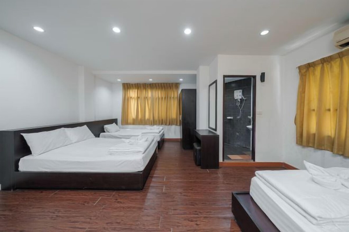 Habitación de hotel con una cama grande, una cama más pequeña, zona de estar y baño con puerta de cristal.