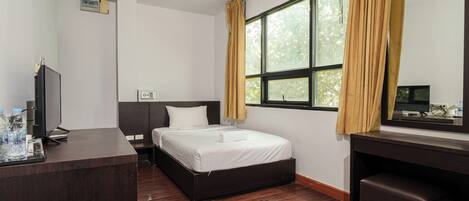 A hotel room with a bed, a desk, a television, and a window with curtains.