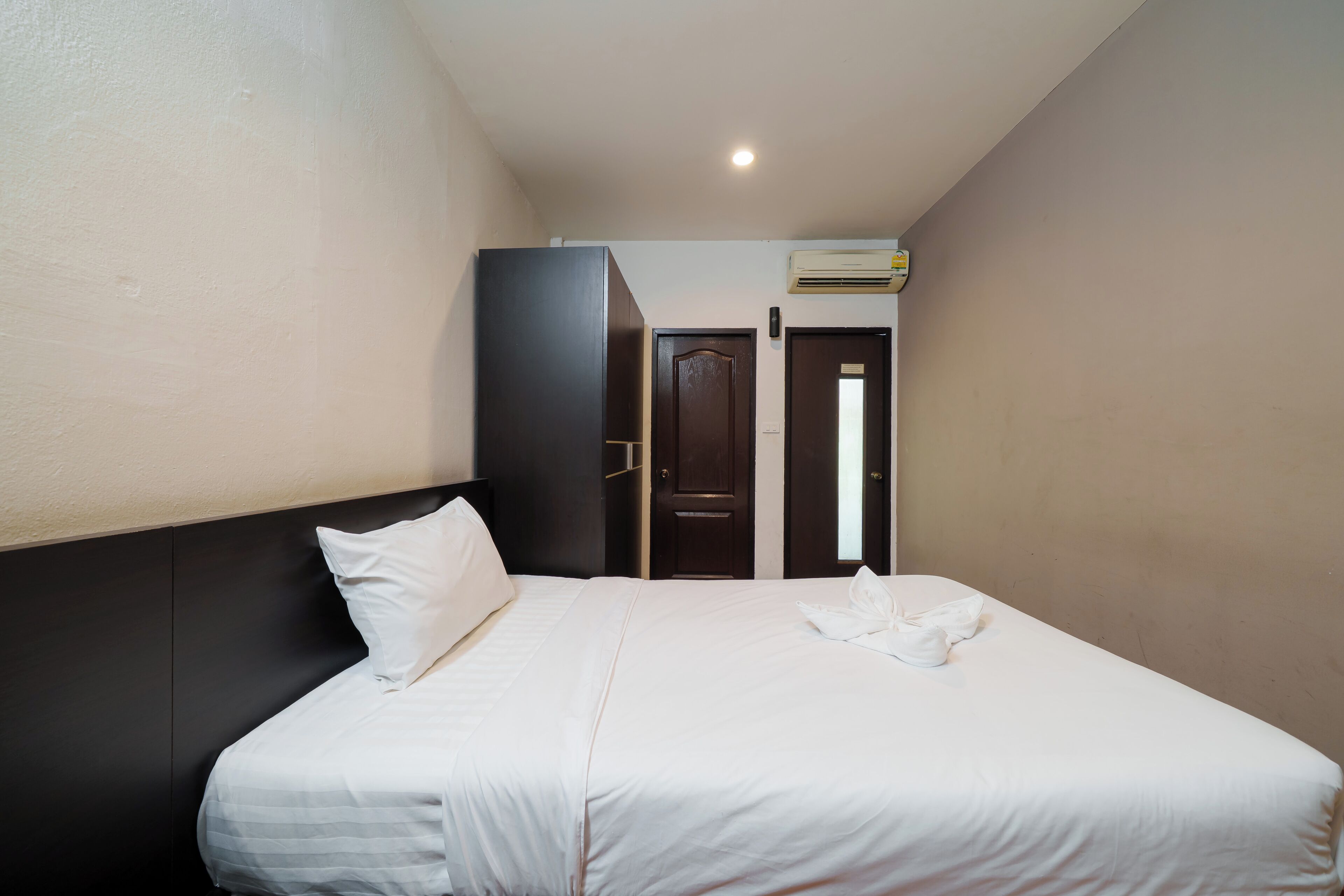 A hotel room with a bed, a wardrobe, and a door leading to another room.