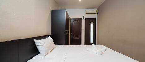 A hotel room with a bed, a wardrobe, and a door leading to another room.