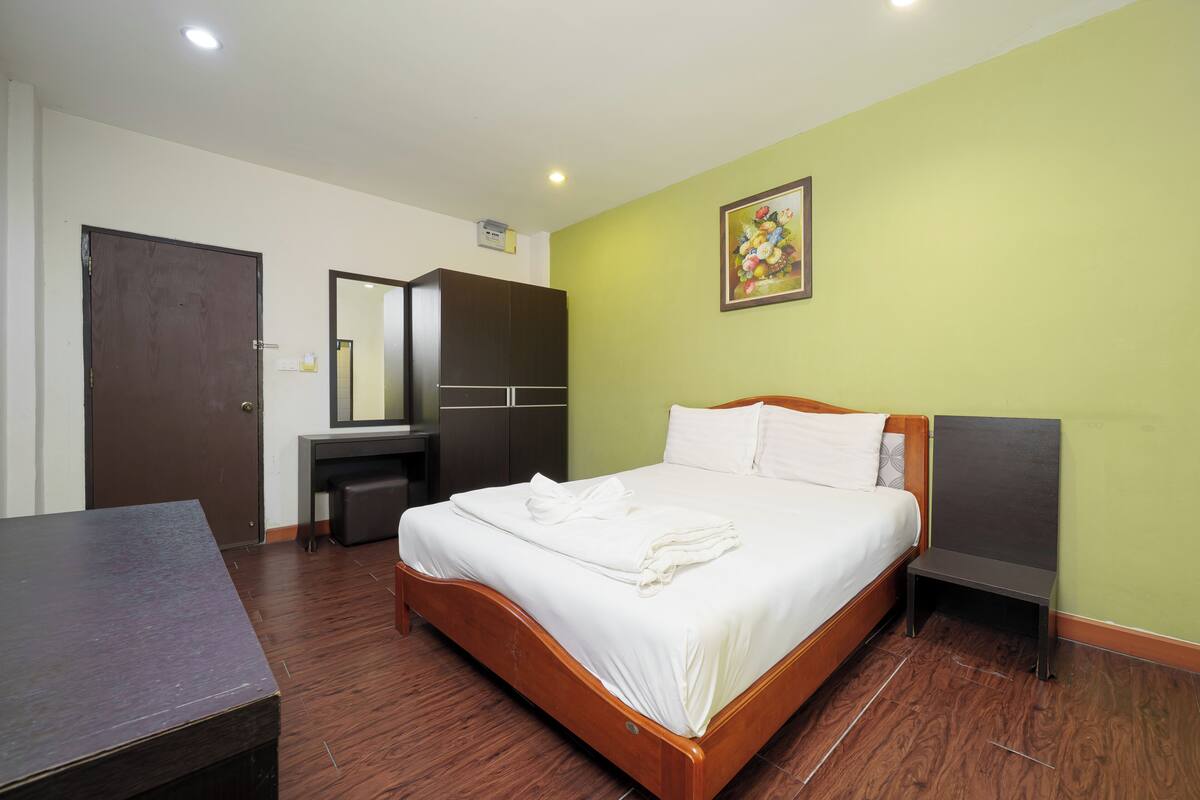 Una habitación de hotel ordenada con una cama, un escritorio y un armario.
