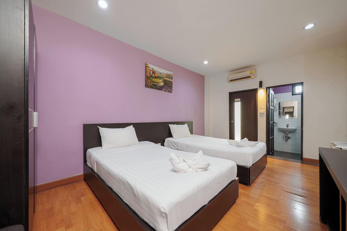 Habitación de hotel con dos camas, una pared morada y un cuadro.
