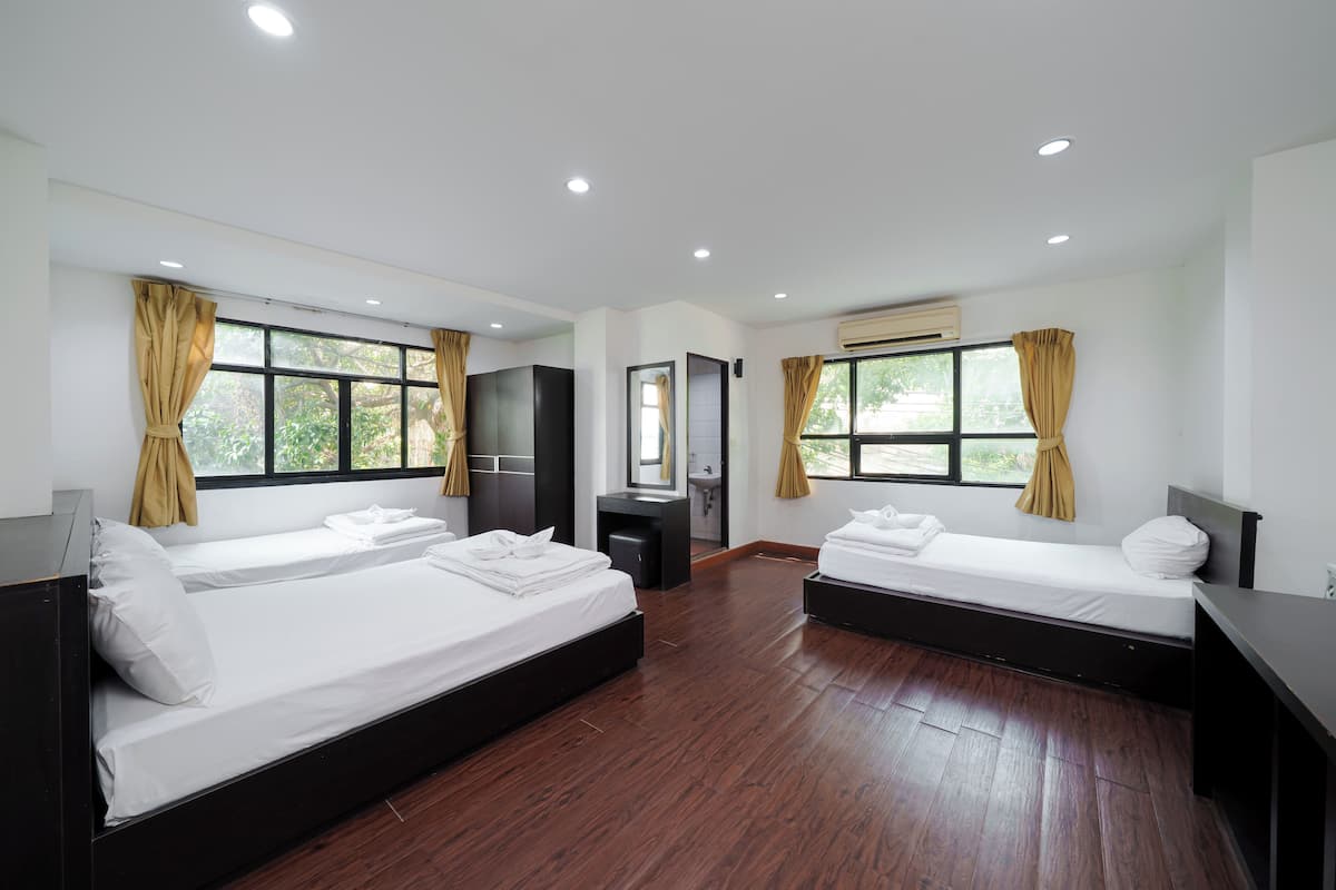 Habitación de hotel con dos camas, un escritorio pequeño, un espejo y una ventana con cortinas.