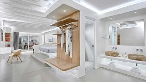 Une chambre d’hôtel moderne au design minimaliste, dotée d’un grand miroir, d’une coiffeuse en bois et d’un coin salon avec un fauteuil.