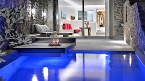 Un espace spa moderne doté d’un plancher chauffant, d’un coin salon avec vue et d’un mur en pierre.