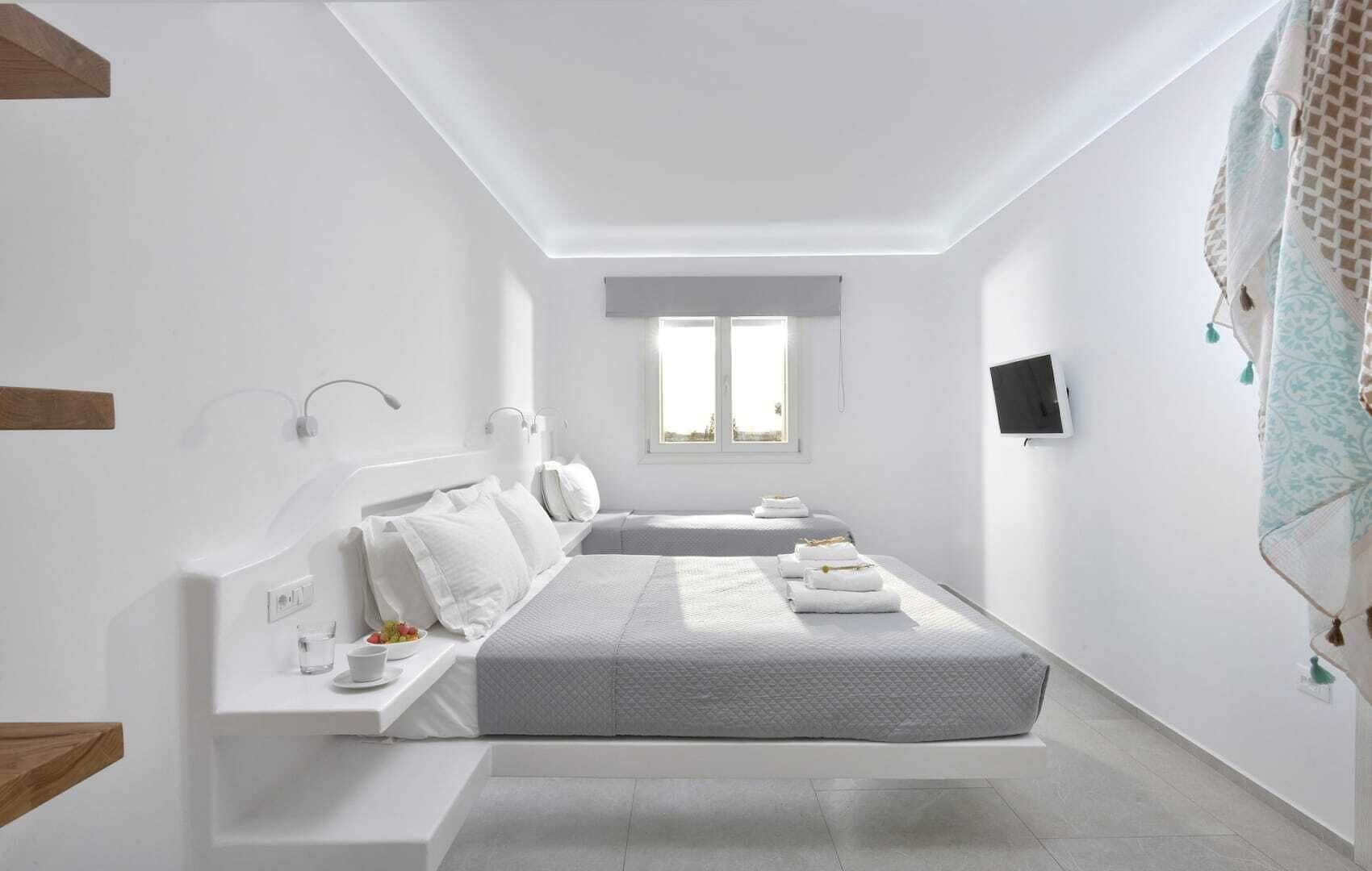 A modern bedroom with a large bed, bedside tables, a TV, and a window.