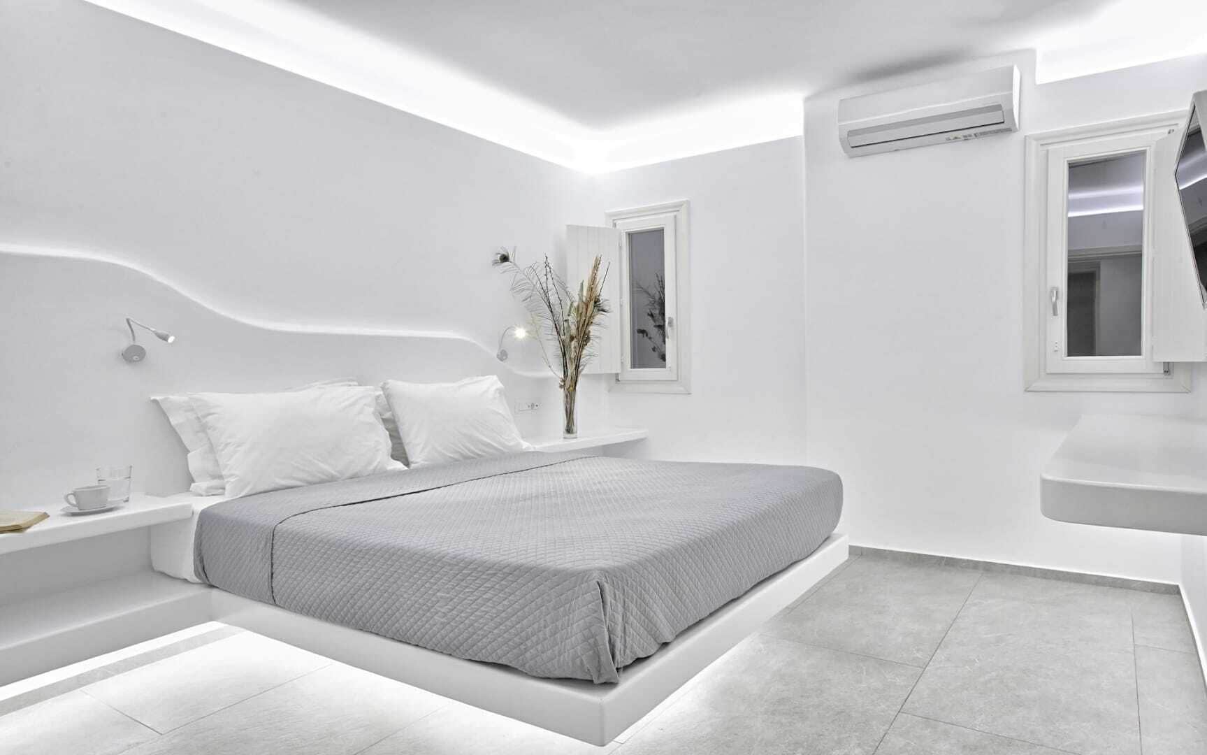 A modern bedroom with a bed, bedside table, and a window with a view.