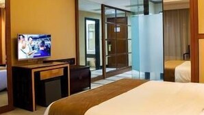 A hotel room with a bed, a television, a desk, and a glass partition. - Kinglong Hotel (Dongguan)