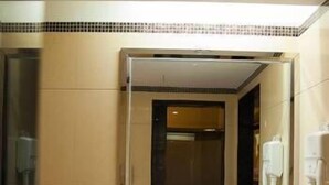 A hotel bathroom with a large mirror, a sink, and a telephone. - Kinglong Hotel (Dongguan)
