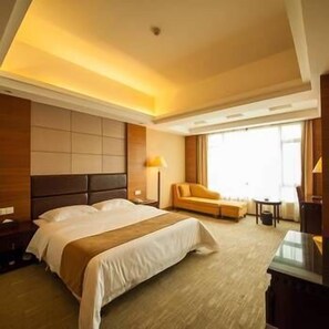 Ein Hotelzimmer mit einem großen Bett, einer Couch, einem Schreibtisch und einem Fenster.