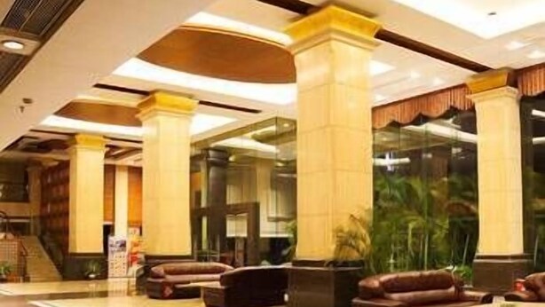 A spacious lobby with high ceilings, large columns, and leather seating areas. - Kinglong Hotel (Dongguan)