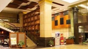 A spacious lobby with a central open area, a staircase, and a seating area with a table and chairs. - Kinglong Hotel (Dongguan)