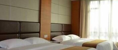 Habitación de hotel con dos camas, un ventanal con cortinas y un cabecero moderno.