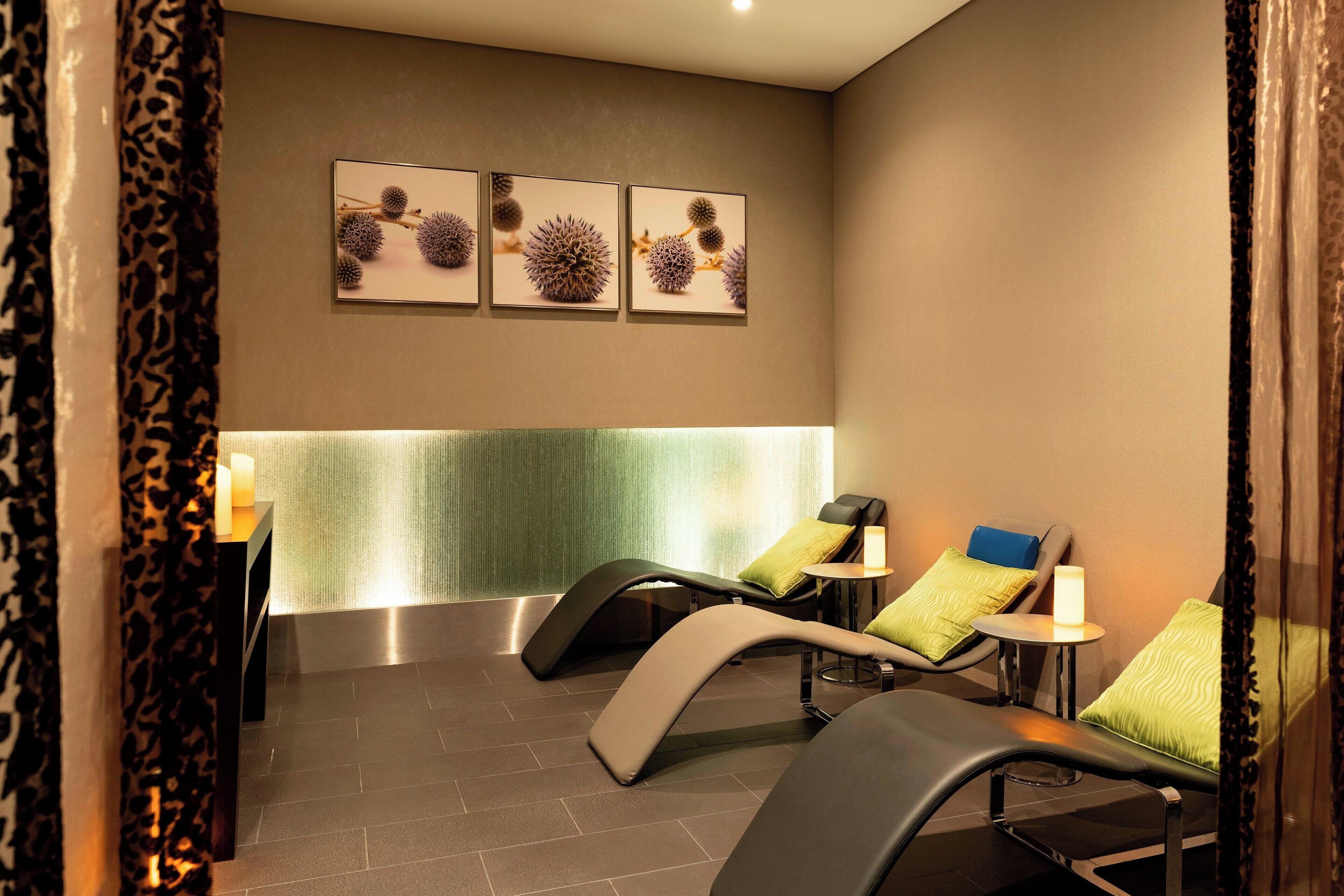 Un cuarto de spa con dos sillas reclinables, una mesita con una vela y tres cuadros en la pared.