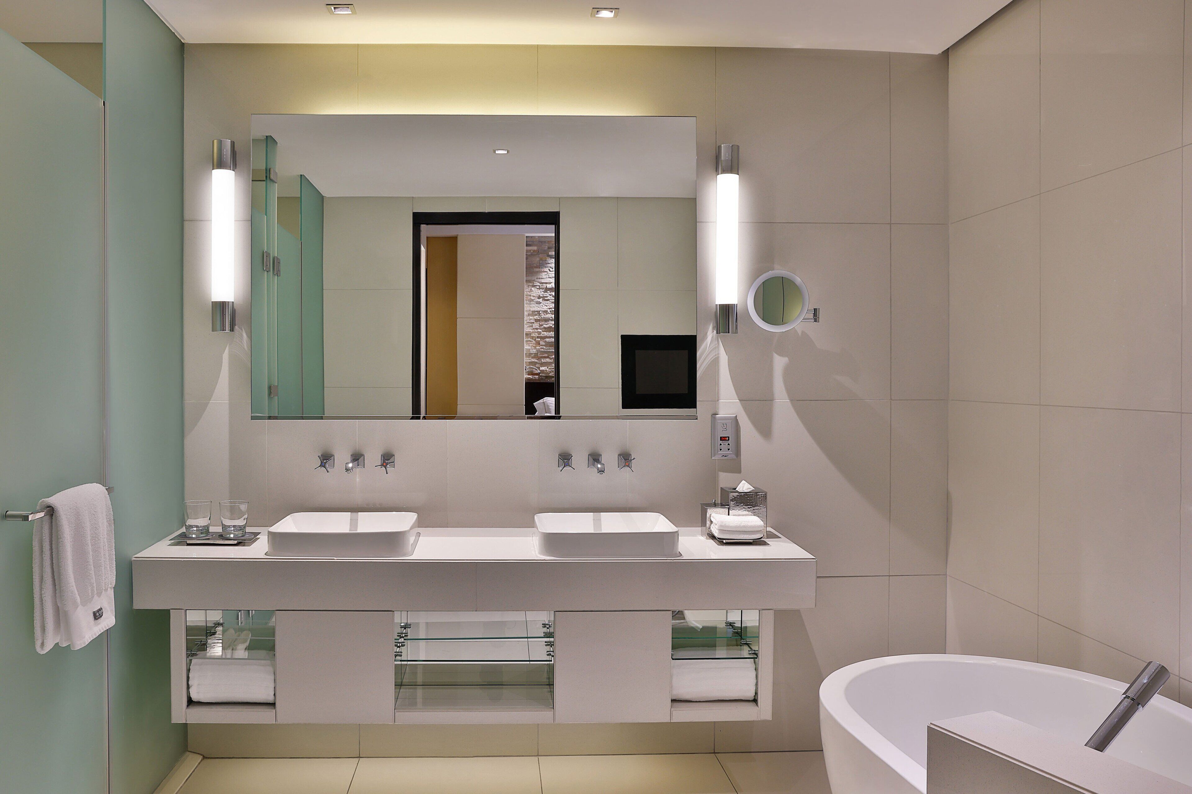 Un bagno moderno con un doppio lavabo, un ampio specchio e una vasca da bagno freestanding.