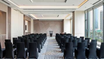 Un salón de conferencias con filas de sillas, un atril y una alfombra estampada.