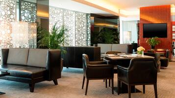 Un moderno vestíbulo de hotel con un sofá, una mesa de comedor, sillas y una televisión.